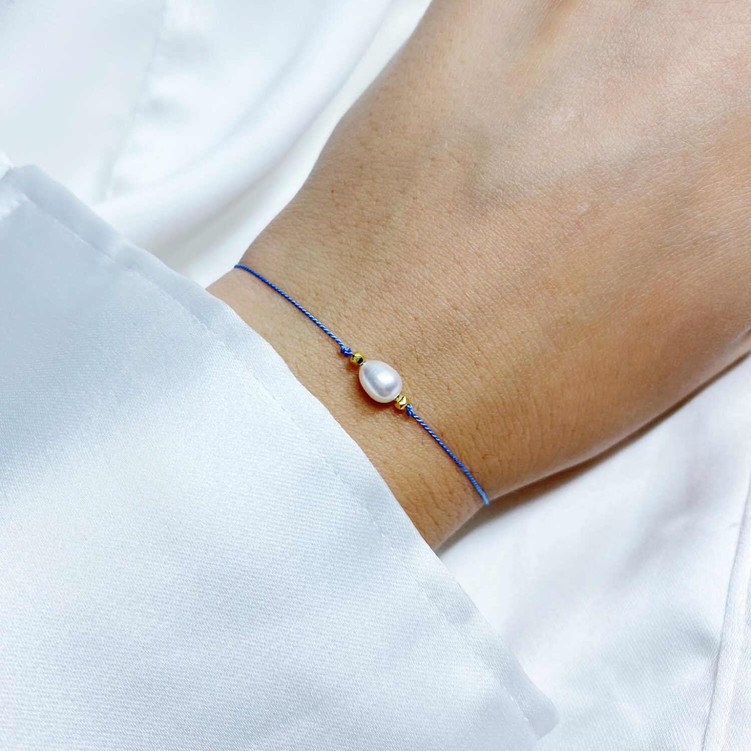bransoletka przyjaźni na niebieskiej nici jedwabnej ozdobiona perłą naturalną i złotym hematytem